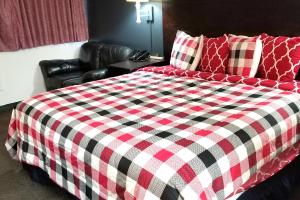 a bed with a red and black checkered blanket at Sky-Palace Inn & Suites Hutchinson in Hutchinson