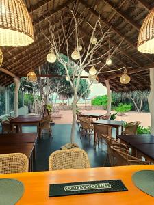 restauracja ze stołami, krzesłami i drzewem w obiekcie Sleeping Elephant Beach Resort w Tangalli