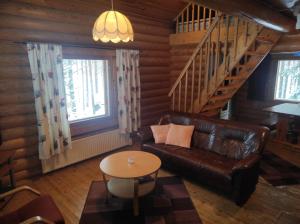 a living room with a leather couch and a staircase at Kalliorinteen Mökit Ruskapirtti in Töysä