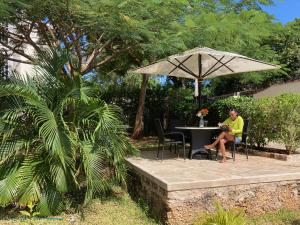 a man sitting in a chair under an umbrella at Hilda's Homestay in Diani Beach