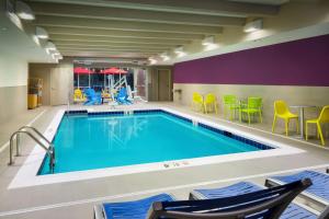 a pool in a hotel room with chairs and tables at Home2 Suites By Hilton Richmond Glenside in Richmond