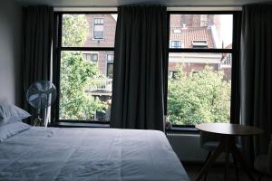 a bedroom with a bed and two large windows at Boutique Hotel Johannes in Delft
