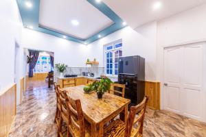 a dining room with a wooden table and a kitchen at Trà My Villa Đà Lạt in Da Lat