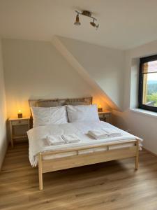 a bedroom with a bed with white sheets and pillows at Apartmán Plešivec ALL4FUN u sjezdovky in Abertamy