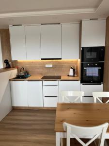 a kitchen with white cabinets and a table and chairs at Apartmán Plešivec ALL4FUN u sjezdovky in Abertamy