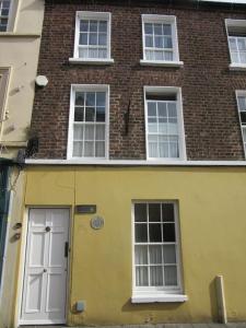 a yellow building with a white door and windows at Darcus Cottage in Derry Londonderry