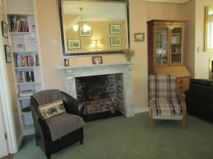 a living room with a fireplace and a mirror at Darcus Cottage in Derry Londonderry