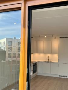 a kitchen with white cabinets and a large window at TotalApartments Vervet Gjøa, brand new apartments in Tromsø