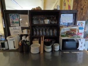 a counter with a microwave and a shelf with plates at Zamamia International Guesthouse in Shimajiri