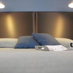 a bed with blue pillows and a book on it at Hotel Marina Piccola in Manarola