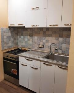 Apartment on Vazha-Pshavela VI, 1A في تبليسي: مطبخ بدولاب بيضاء ومغسلة وموقد