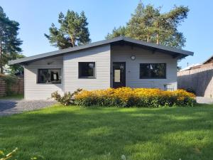 a small white house with a grass yard at Chalet Little Cocoon in Tellin