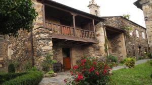 an old stone building with a balcony and red flowers at Casa de Alba in San Martín de Oscos