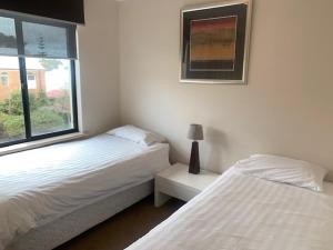 two white beds in a room with a window at Villa 11 in Fremantle