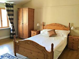 a bedroom with a large wooden bed with white sheets at Les Verges Gites in Exideuil