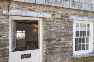 a brick building with a white door and a window at Mobray, Port Isaac Bay Holidays in Port Isaac +7 photos