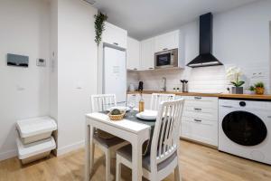 kuchnia ze stołem i krzesłami oraz pralką w obiekcie Nordik Apartments Urban - Centro "Oslo" w Maladze