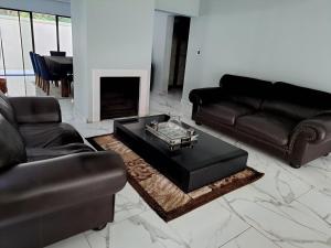 sala de estar con muebles de cuero negro y chimenea en Charis on Beaumont Home, en Ramsgate
