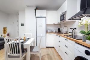 kuchnia z białymi szafkami oraz stołem i krzesłami w obiekcie Nordik Apartments Urban - Centro "Oslo" w Maladze