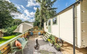 a tiny house with a patio with a table and chairs at Cozy Cobblers Cabin in Dallington