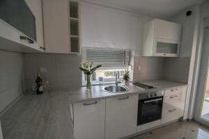 una cocina con armarios blancos y fregadero en Apartment Matea, en Banjole