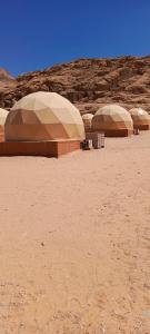 a group of three domed buildings in the desert at Wadi Rum Marcanã camp in Aqaba