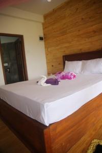 - un grand lit avec une tête de lit en bois et des draps blancs dans l'établissement Mountain Range Cottage, à Ella