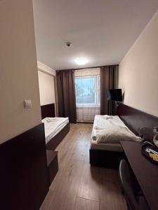 a room with two beds and a desk and a window at Noclegi Gambit Cieszyn 24h in Cieszyn