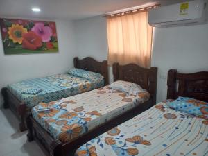 two twin beds in a room with a window at Hotel heliconias mompox in Mompós +21 photos