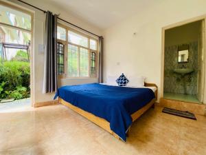 1 dormitorio con cama con sábanas azules y ventana en Rahgir Mcleodganj en McLeod Ganj