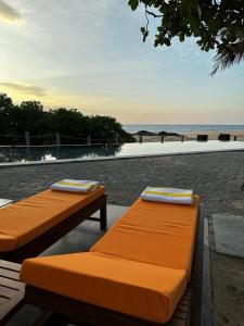 two orange beds sitting next to the beach at The Postcard on the Arabian Sea in Udupi
