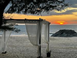 a bed on the beach with the sunset in the background at The Postcard on the Arabian Sea in Udupi
