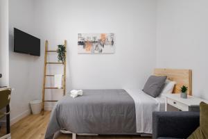 a white bedroom with a bed and a tv at Nordik Rooms Urban - Centro "Estocolmo" in Málaga