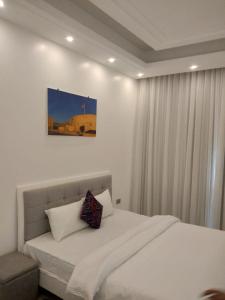 Un dormitorio con una cama blanca con una foto en la pared en MY HOTEL Al Lathba Pool Villa - Nizwa فيلا اللثبه-نزوى, en Nizwa