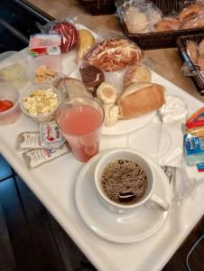 una bandeja de comida con una taza de café y pan en Calabreza Hotel e Restaurante - By UP Hotel, en Três Corações