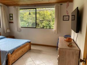 een slaapkamer met een bed en een groot raam bij Casa de campo Cutucumay in Chinauta