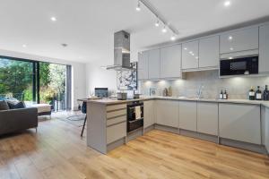 a kitchen with white cabinets and a living room at Private En-suite Double Rooms - 5 Minute Walk to Hendon Central Station - Reach Central London in just 21 Minutes in Golders Green