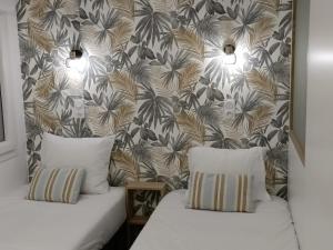 two beds in front of a wall with a tropical wallpaper at Cosy Aulnay-Paris Nord -Expo Villepinte-Stade de France in Aulnay-sous-Bois