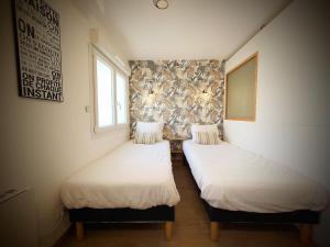 two twin beds in a room with a wall at Cosy Aulnay-Paris Nord -Expo Villepinte-Stade de France in Aulnay-sous-Bois