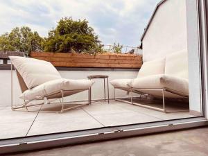 two white chairs and a table on a balcony at Luxus Loft im Herzen von Bochum Werne. in Bochum