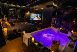 a room with a tub with a bed and a television at Minka Cocon Atypique avec jacuzzi privé in Corbas +14 photos