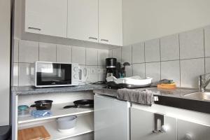 eine Küche mit einer Spüle und einer Mikrowelle in der Unterkunft Charmant studio au rez de chaussée. in Denain