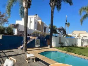 uma casa com piscina e palmeiras em La villa des corsaires, vue panoramique sur Rabat em Salé