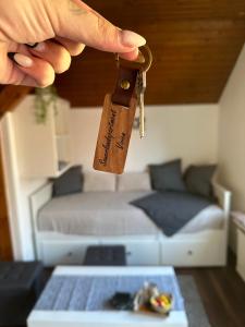 a person holding a pair of keys in front of a bed at Sauerlandapartment Vivien in Plettenberg