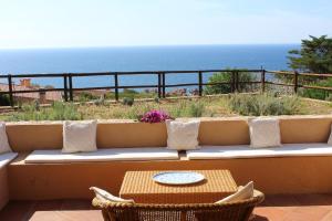 un sofá con mesa y sillas y el océano en Residence La Cala infinityholidays, en Costa Paradiso