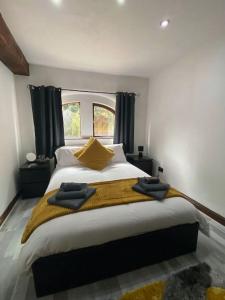 a bedroom with a large bed with yellow pillows at The Coach House by Phoenix Premises - Hot Tub Fire Pit BBQ Log Burner Bar Games Room in Birmingham