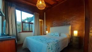 1 dormitorio con cama y ventana grande en Altos del Sol - Spa & Resort en Merlo