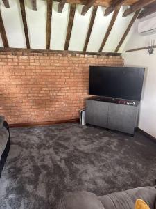 a living room with a flat screen tv and a brick wall at The Coach House by Phoenix Premises - Hot Tub Fire Pit BBQ Log Burner Bar Games Room in Birmingham