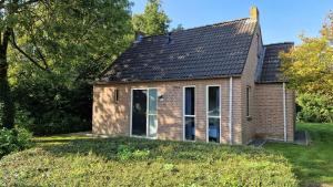 a small brick house on a grassy field at Forestview 'Queenstown' 6 pers very child-friendly by Kawatea Cottages in Ewijk