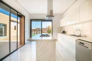 une cuisine avec des placards blancs et une grande fenêtre dans l'établissement Villa Sakina, piscine Chauffée, ping-pong, cuisinière, à Marrakech